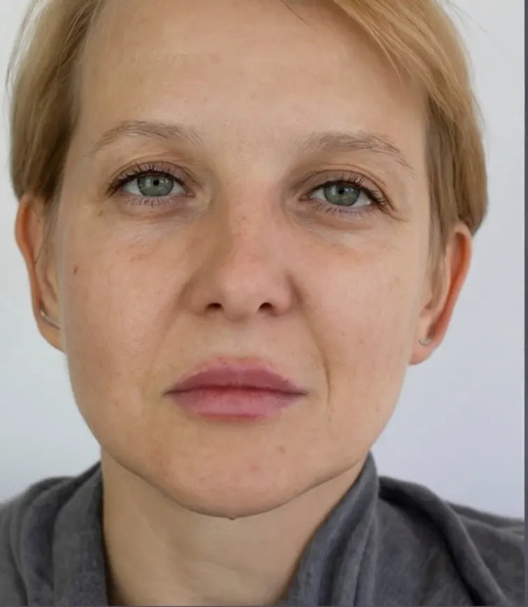 Close-up of a person with short blonde hair and a neutral expression on a plain background