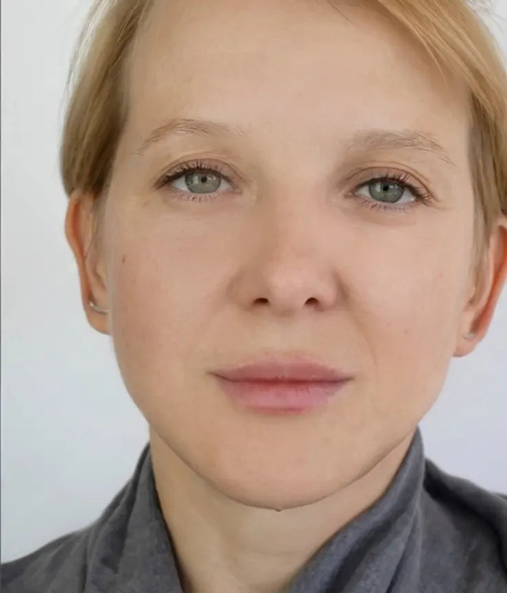 Close-up of a person with blonde hair and green eyes on a plain background